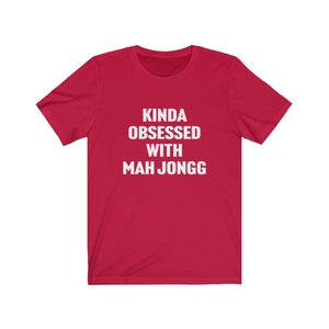 May include: Red short-sleeved t-shirt with white text that reads "Kinda obsessed with Mah Jongg".