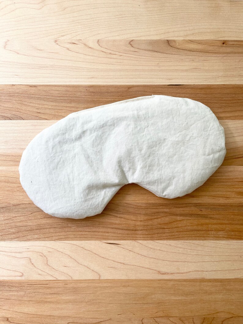 May include: A white cotton eye mask for sleeping. The mask is filled with flax seeds and lavender.