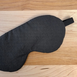 May include: A black sleep mask with an elastic strap. The mask is made of a soft, comfortable fabric.