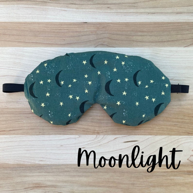 May include: A green sleep mask with a crescent moon and star pattern. The text "Moonlight" is printed below the mask.
