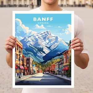 May include: A vintage travel poster featuring a colorful illustration of Banff, Canada. The poster depicts a mountain range with snow-capped peaks, a street lined with buildings, and a blue sky with white clouds. The text "BANFF CANADA" is printed in white at the top of the poster.