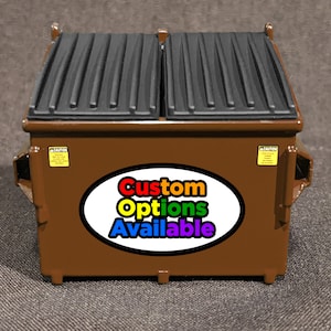 May include: A brown metal dumpster with a black lid. The dumpster has a sticker that says "Custom Options Available" in rainbow colors.