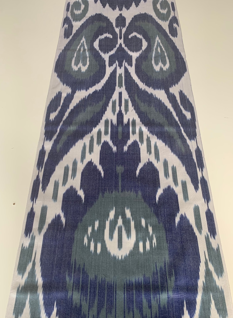 Puede incluir: Una tela blanca con un patr&oacute;n ikat azul y verde. El patr&oacute;n es un dise&ntilde;o tradicional con un motivo repetitivo de hojas y flores.