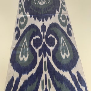 Puede incluir: Una tela blanca con un patr&oacute;n ikat azul y verde. El patr&oacute;n es un dise&ntilde;o tradicional con un motivo repetitivo de flores y hojas estilizadas.
