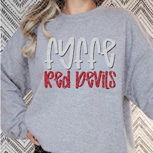 May include: A heather gray crewneck sweatshirt featuring the text "FYFFE" in large white letters with a black outline, positioned above the words "RED DEVILS" in bold red letters with a black outline, centered on the chest of the garment.