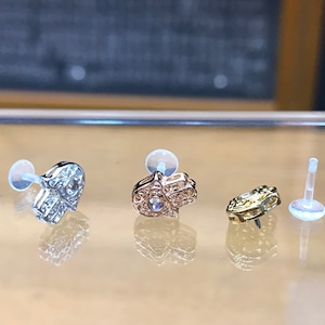 May include: Three different styles of heart-shaped jewellery pieces with clear stones. The pieces are on a white surface and are ready to be worn.