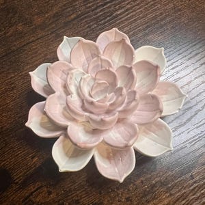May include: A ceramic succulent sculpture shaped like a blooming flower with layered, pointed petals. The petals feature a gradient color scheme, transitioning from a soft, pale pink at the center to a clean, solid white at the outer edges.
