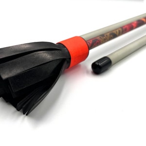 May include: A black and red juggling club with a black foam tip. The club has a red band around the middle and a patterned design.
