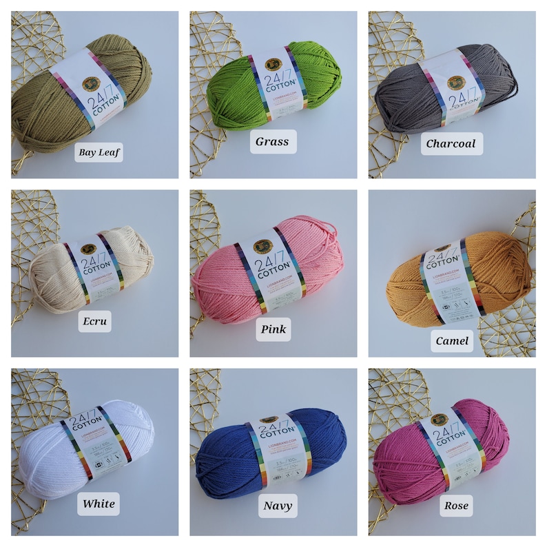 K&ouml;nnte beinhalten: Neun Str&auml;nge Lion Brand 24/7 Baumwollgarn in verschiedenen Farben. Farben sind Bay Leaf, Grass, Charcoal, Ecru, Pink, Camel, White, Navy und Rose. Jeder Strang hat ein Etikett mit dem Markennamen und der Garnart.