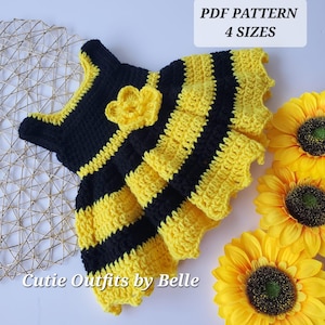 May include: A crochet baby dress with yellow and black stripes, resembling a bee. The dress has a flower embellishment and is available in four sizes. The text "PDF PATTERN 4 SIZES" and "Cutie Outfits by Belle" are visible in the image.