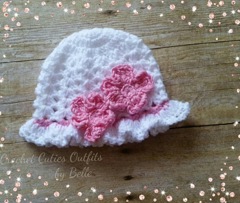 May include: White crocheted sun hat with a pink crocheted flower embellishment. Crochet Cuties Outfits by Belle.
