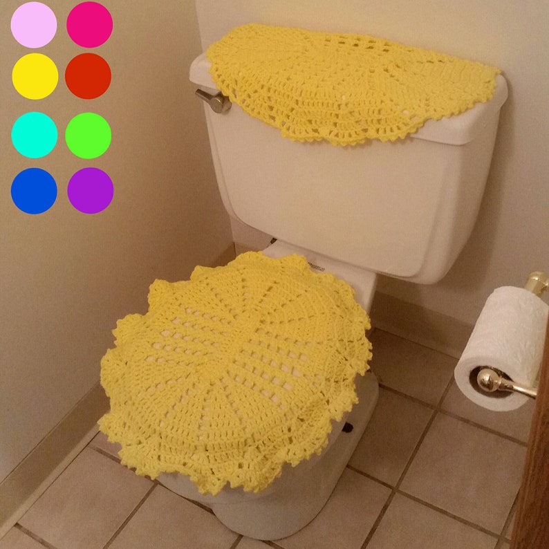 May include: A yellow crocheted toilet seat cover and tank cover. The cover is made of a delicate, lacy pattern.