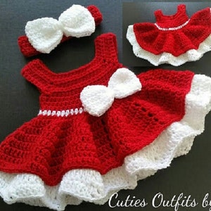 Pode incluir: Um vestido de beb&eacute; de crochet vermelho com acabamento de crochet branco e um la&ccedil;o de crochet branco. O vestido tem uma faixa de cabe&ccedil;a de crochet branco com um la&ccedil;o.