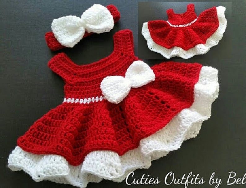 Pode incluir: Vestido de beb&eacute; de croch&ecirc; vermelho com acabamento de croch&ecirc; branco e um la&ccedil;o branco. O vestido tem uma faixa de cabe&ccedil;a de croch&ecirc; branco com um la&ccedil;o.