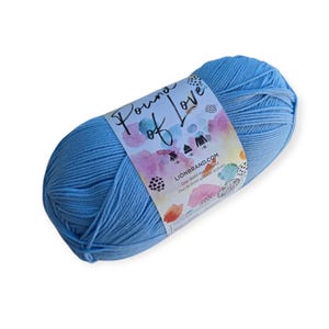 May include: A skein of light blue yarn with a white paper label featuring the text Pound of Love and LIONBRAND.COM. The label includes watercolor-style splotches in pink, orange, and blue, along with small black icons of a hat and sweater.