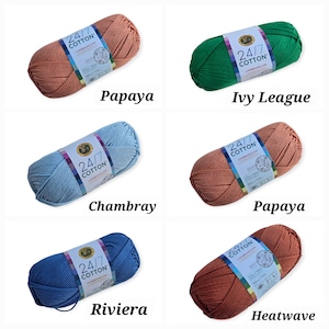 K&ouml;nnte beinhalten: Sechs Kn&auml;uel Lion Brand 24/7 Baumwollgarn in verschiedenen Farben, darunter Papaya, Ivy League, Chambray, Riviera und Heatwave. Jedes Kn&auml;uel hat ein Etikett mit Markennamen und Produktdetails. Das Garn eignet sich zum Stricken und H&auml;keln.