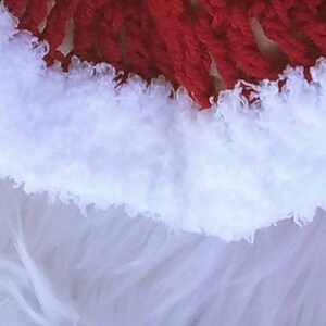 May include: Close-up of a white fluffy yarn with a red yarn border. The white yarn is soft and textured, while the red yarn is smooth and tightly woven.