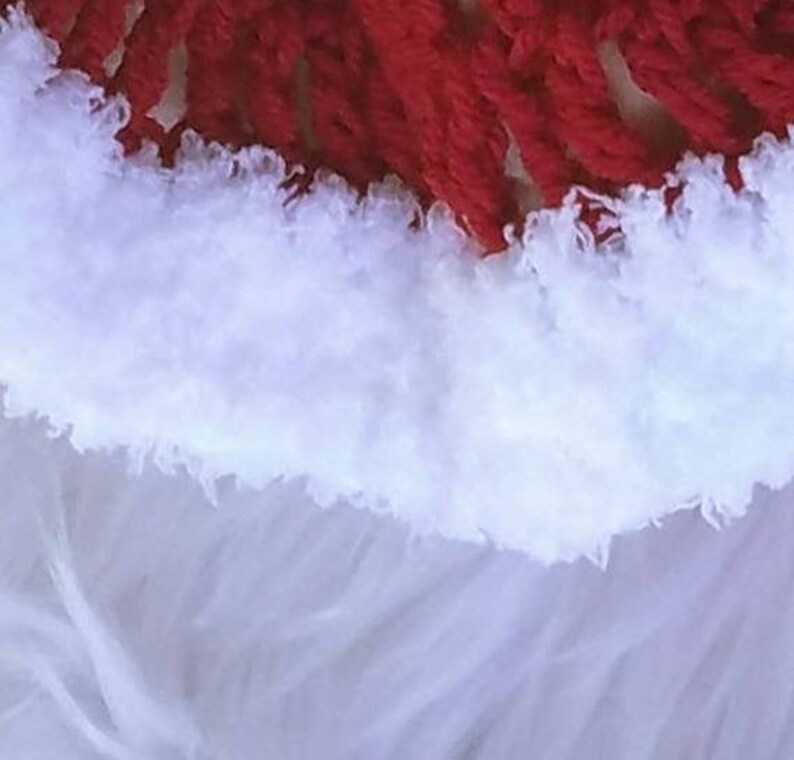 May include: Close-up of a white fluffy yarn with a red yarn border. The white yarn is soft and textured, while the red yarn is smooth and tightly woven.