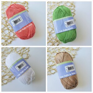 May include: Four skeins of yarn in coral, green, white, and beige. Each skein has a label that reads "Cutie Outfits by Belle". The yarn is arranged on a gold-colored, geometric patterned surface.