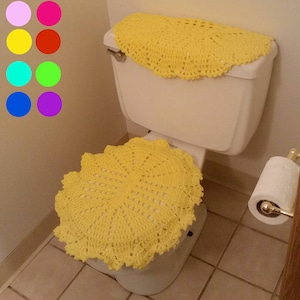 May include: A yellow crocheted toilet seat cover and tank cover. The cover is made of a delicate, lacy pattern.