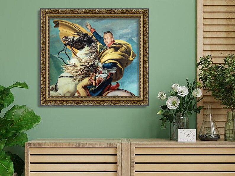 May include: A framed painting of a person riding a white horse. The person is wearing a yellow and blue outfit and a yellow cape. The background is a blue sky with white clouds.