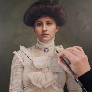Op de afbeelding: Een olieverfschilderij van een persoon met donker haar in een opgestoken kapsel, gekleed in een crèmekleurige blouse met een hoge kraag, kanten details en een grote strik op de borst. Een kleine ronde broche met een blauwe steen zit op de kraag.