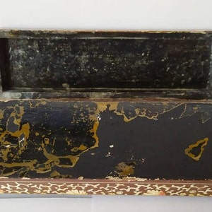 May include: An antique wooden box with a black interior and gold accents. The box is decorated with a floral pattern and has a hinged lid.