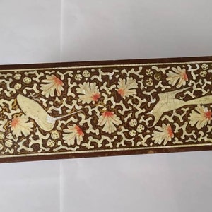 May include: A rectangular wooden box with a decorative design. The box is brown with a white and gold floral pattern and two birds in flight.