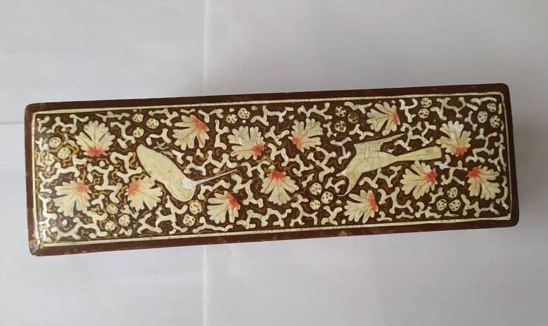 May include: A rectangular wooden box with a decorative design. The box is brown with a white and gold floral pattern and two birds in flight.