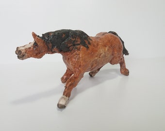 May include: A brown and black horse figurine in a running pose. The sculpture has a textured surface and is set against a white background. The horse's mane and tail are dark, and its legs are in motion.
