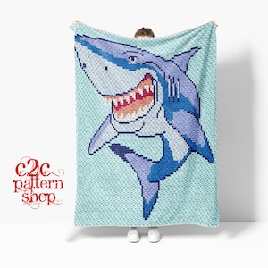 May include: A blue and white crocheted blanket featuring a large, smiling shark with sharp teeth. The blanket is made using the C2C crochet technique.