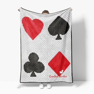 May include: A white crocheted blanket featuring playing card suits: a red heart, a black spade, a black club, and a red diamond. The blanket has a black border and the text "Crochet Studio" in red.