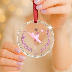 May include: A clear circular acrylic ornament hanging from a red ribbon. The center features a ballerina in a pink tutu with the text Savannah and Dew Drop Fairy printed in pink script, along with the year 2026 printed in small pink digits.