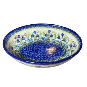 May include: A blue and white oval ceramic serving bowl with a floral pattern and bee accents.