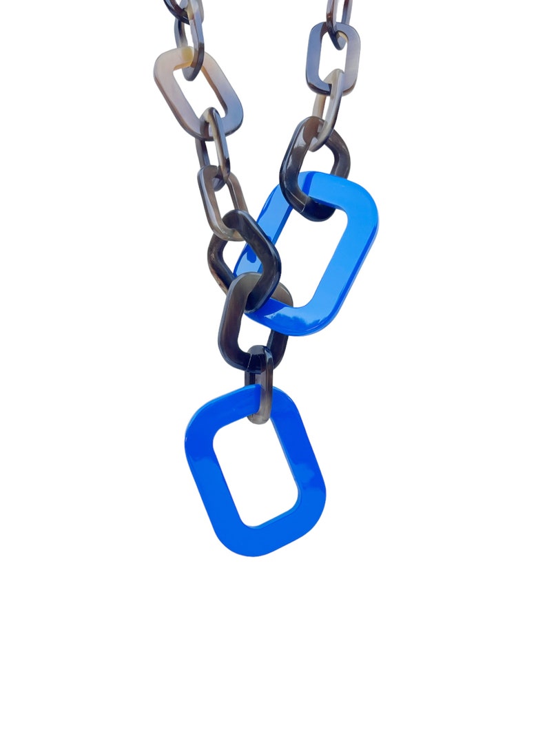 May include: A chain necklace with brown and black links. The chain has two blue rectangular links at the bottom.