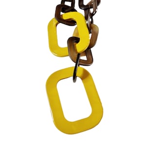 May include: A yellow and brown plastic chain necklace with large, rectangular links.