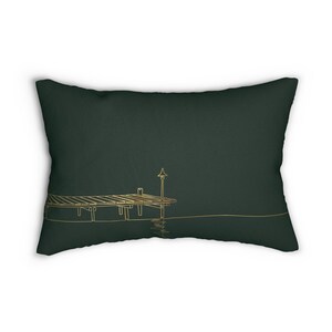 May include: A rectangular throw pillow in a deep forest green color. The front features a minimalist gold-colored line art illustration of a wooden pier extending over water, complete with a single lamp post standing on the edge of the dock.