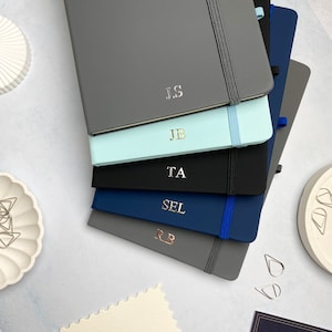 A5 notebooks with personalised foiled initials on the covers. Blue, grey and black notebooks.