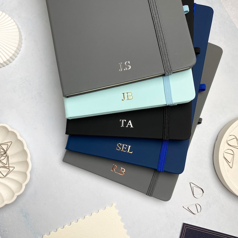 A5 notebooks with personalised foiled initials on the covers. Blue, grey and black notebooks.