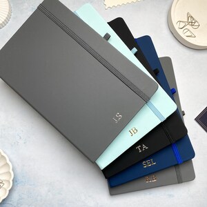 A5 notebooks with personalised initials foil printed centrally at the bottom of the covers. Blue, grey and black notebooks.