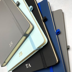 A5 notebooks with personalised initials on the covers. Blue, grey and black notebooks.
