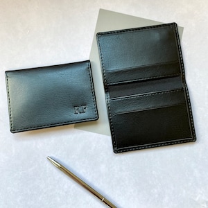 Black card holders with initials, the inside of the card holder is shown which features internal pockets