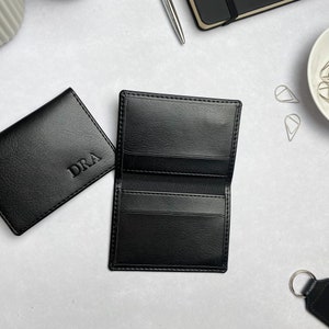 Black card holders with initials, the inside of the card holder is shown which features internal pockets