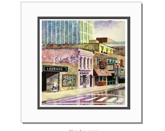 May include: Watercolor painting of a city street scene with storefronts, including "Legends" and "Tootsie's Orchid Lounge." The artwork is 10 inches square, featuring a wet street and a person skateboarding. Buildings are in shades of tan, pink, and green.