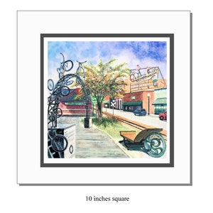 May include: A watercolor painting of a town scene, featuring a bicycle archway and the text "Tennessee Central Trail." The artwork depicts buildings, a railroad crossing, and a vintage cart. The painting is 10 inches square.