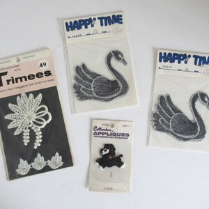 May include: A collection of vintage iron-on appliques and trims. Includes a white lace trim, two black swan patches, and a black poodle applique. The packages have text that reads "Happy Time" and "Trimees".