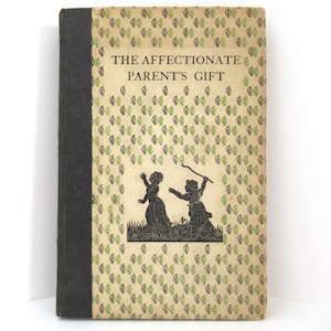 May include: Vintage book titled "The Affectionate Parent's Gift." The cover features a leaf pattern in green and black on a cream background. A black silhouette of two children is in the center. The spine is dark gray.