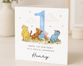 May include: A birthday card featuring Winnie the Pooh characters. The card has a blue number 1, clouds, and stars. Text reads "Happy 1st Birthday to a Special Grandson" and the name "Henry". The card is white with a watercolor style.