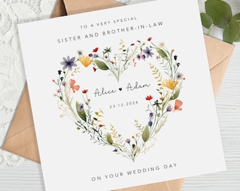 以下が含まれることがあります： 白いウェディングカード。花柄のハートのデザインで、「TO A VERY SPECIAL SISTER AND BROTHER-IN-LAW」と書かれています。「Alice ♥ Adam」の名前と「23.12.2024」の日付も含まれています。「ON YOUR WEDDING DAY」の文字も表示されています。