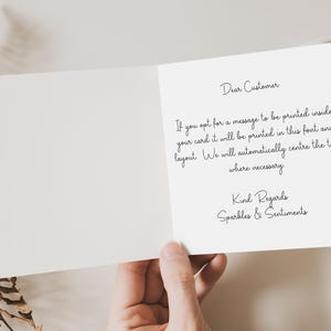 May include: An open greeting card with the text "Dear Customer" and a message about printing. The card is held by a hand, with dried foliage in the background. The card's message is "Kind Regards, Sparkles & Sentiments."